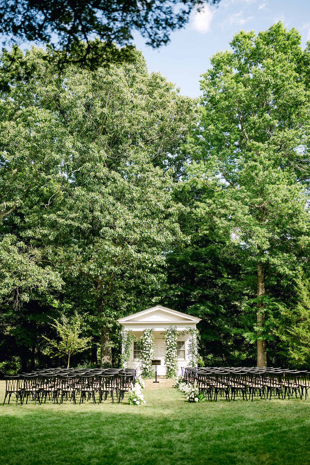 Outdoor ceremony area with small building decorated in floral towers at Wadsworth Mansion