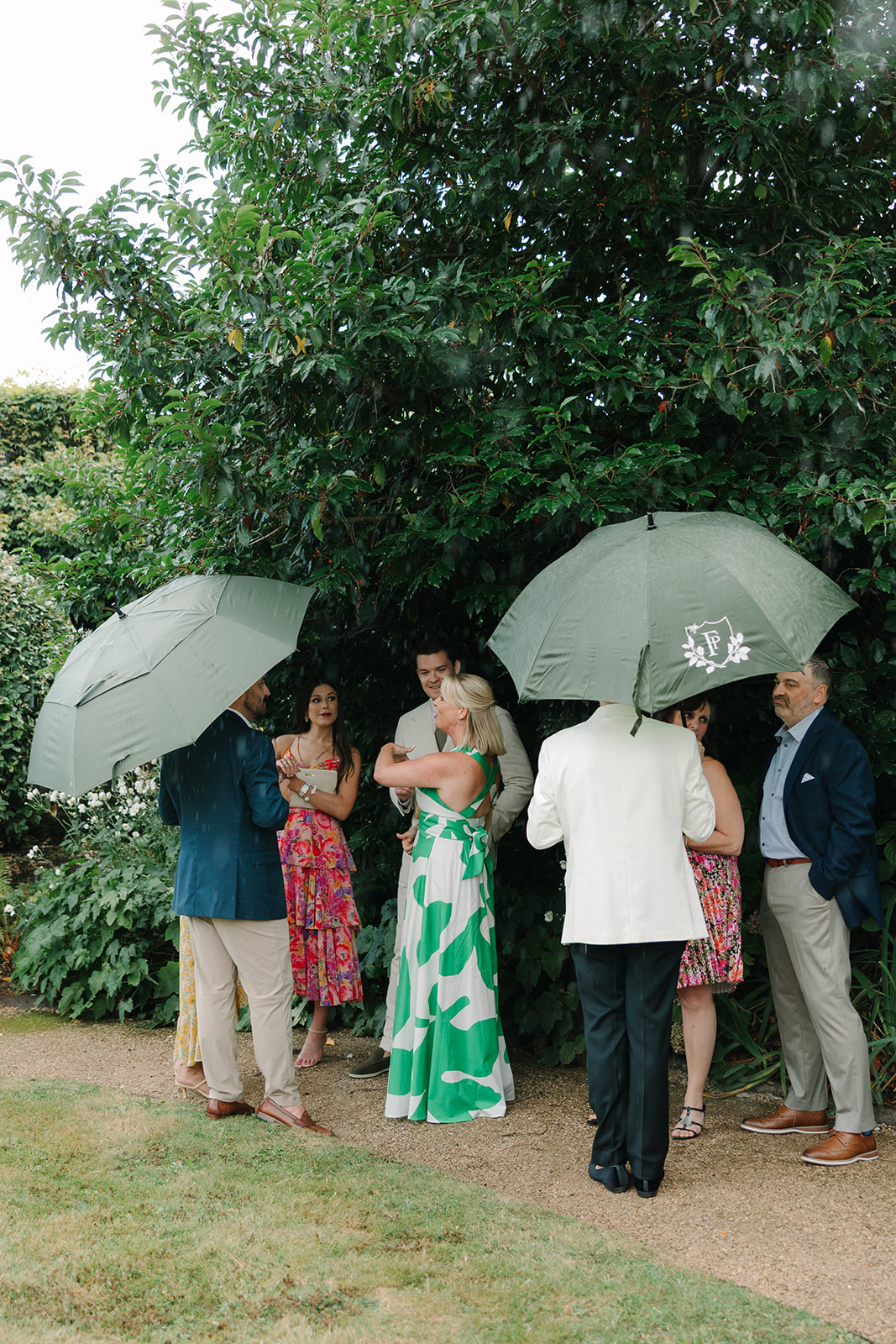 Guests using branded umbrellas for rainy day wedding
