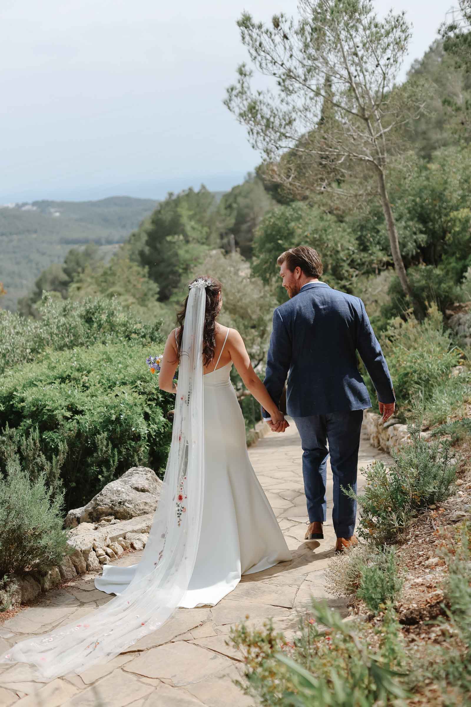 A newly married bride and groom walking in the Catalonian mountains at their wedding venue near Barcelona.