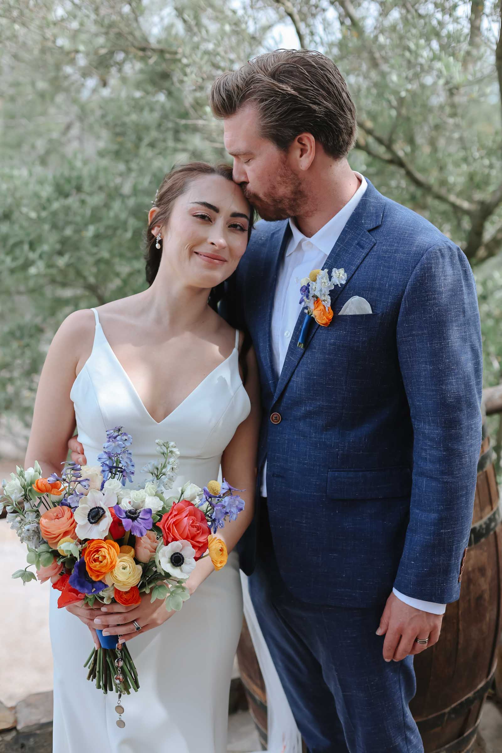 Bride and groom wearing and holding brightly colored flowers for their Spanish destination wedding