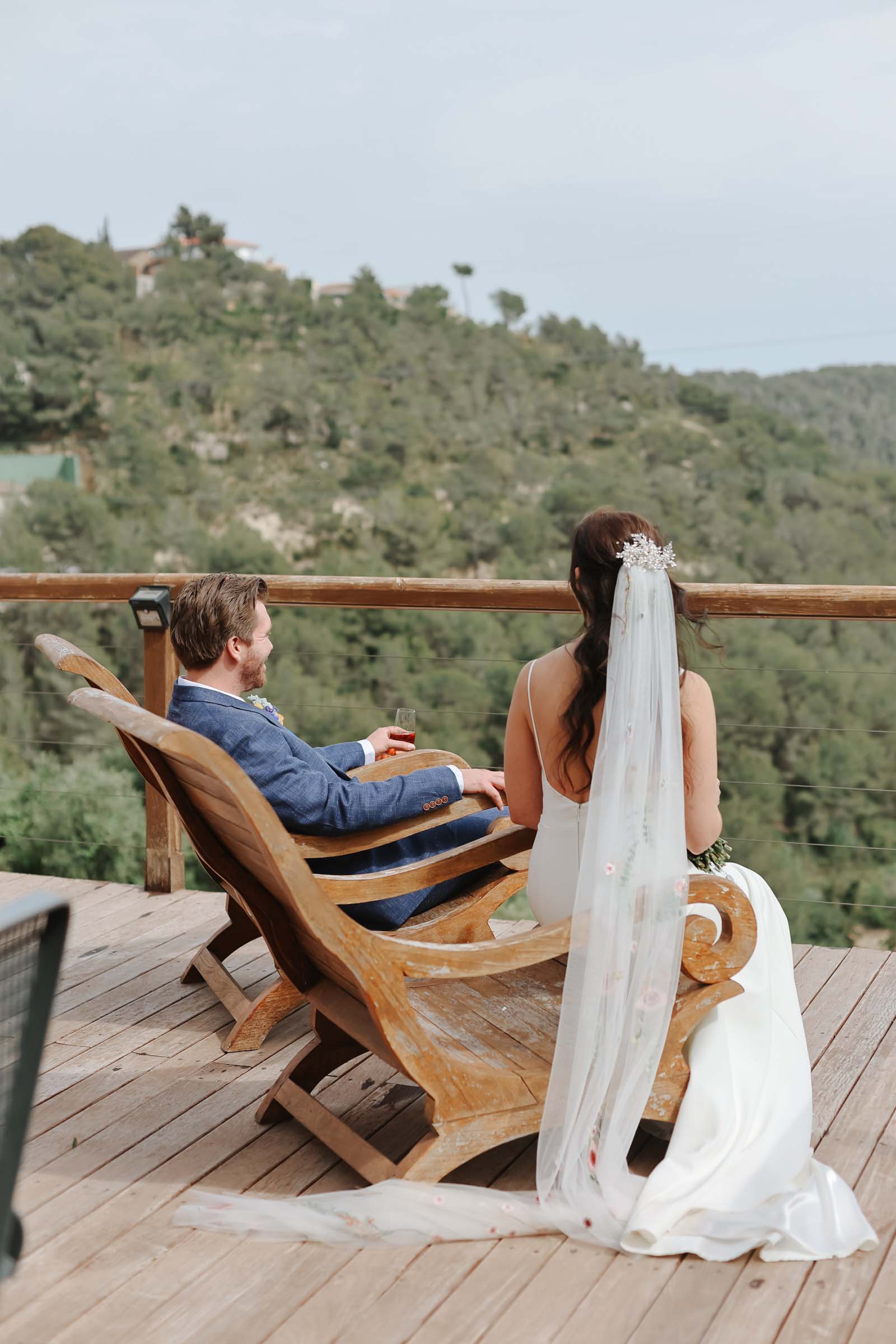 Bride and groom having a quiet moment with a drink looking out across the Catalonian mountains