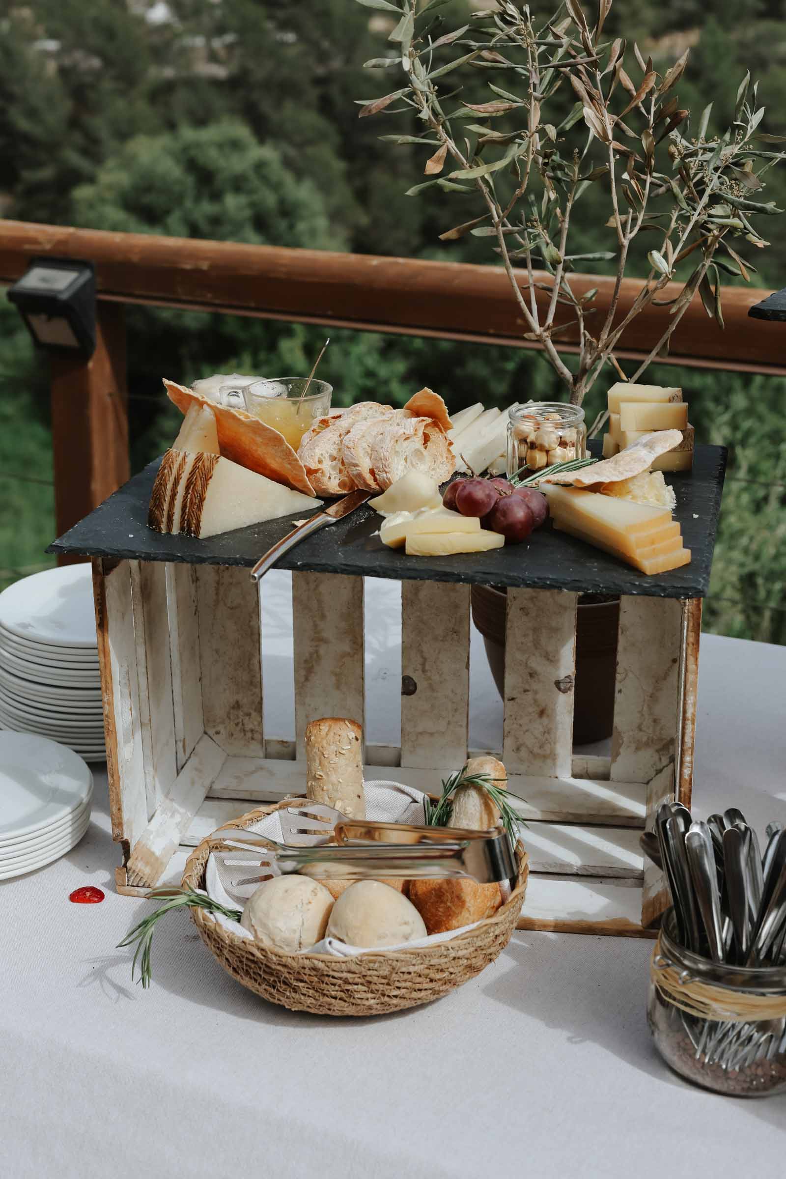 A rustic cheese charcuterie display with bread in baskets for Spanish wedding cocktail hour