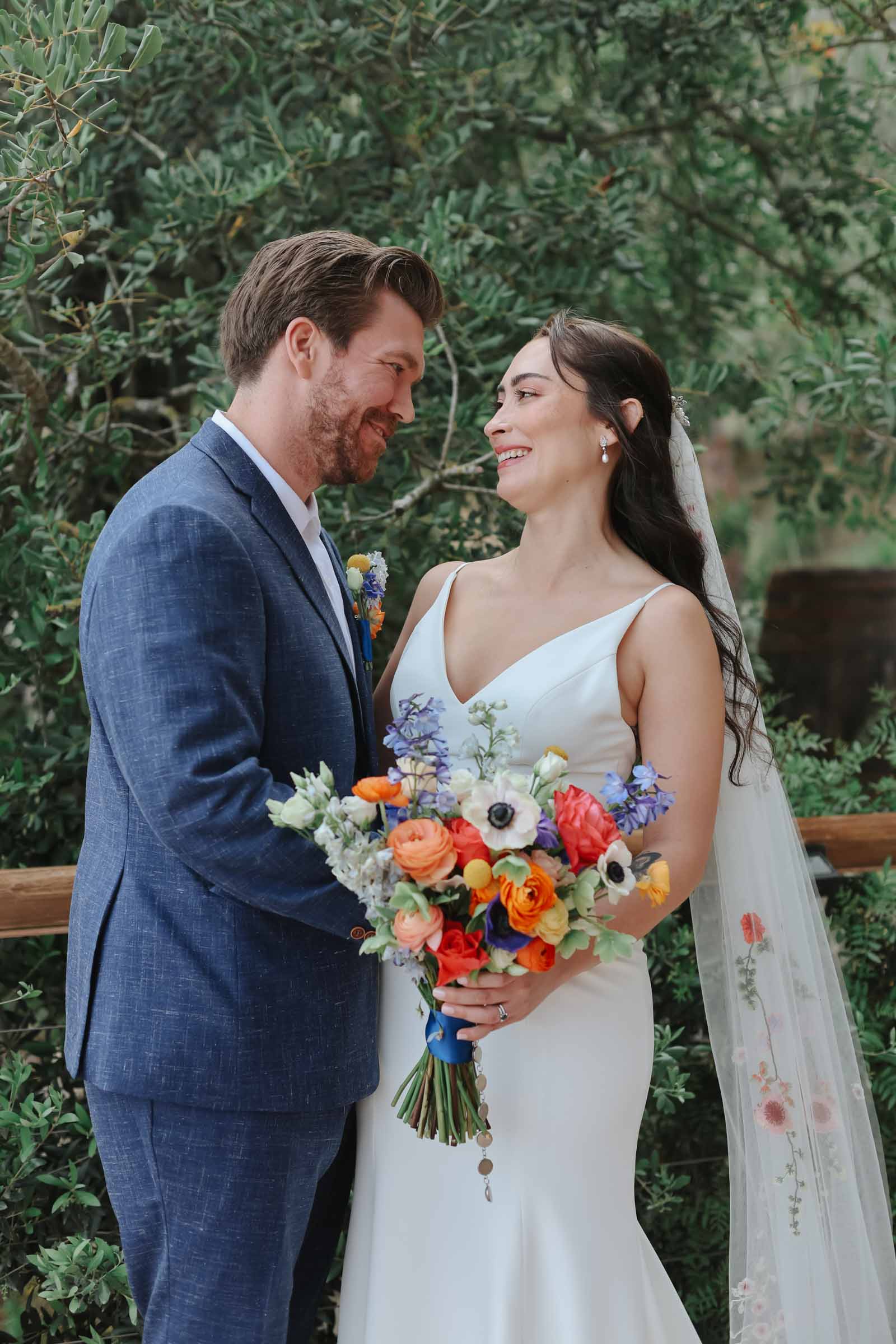 Bride and groom wearing and holding brightly colored flowers for their Spanish destination wedding