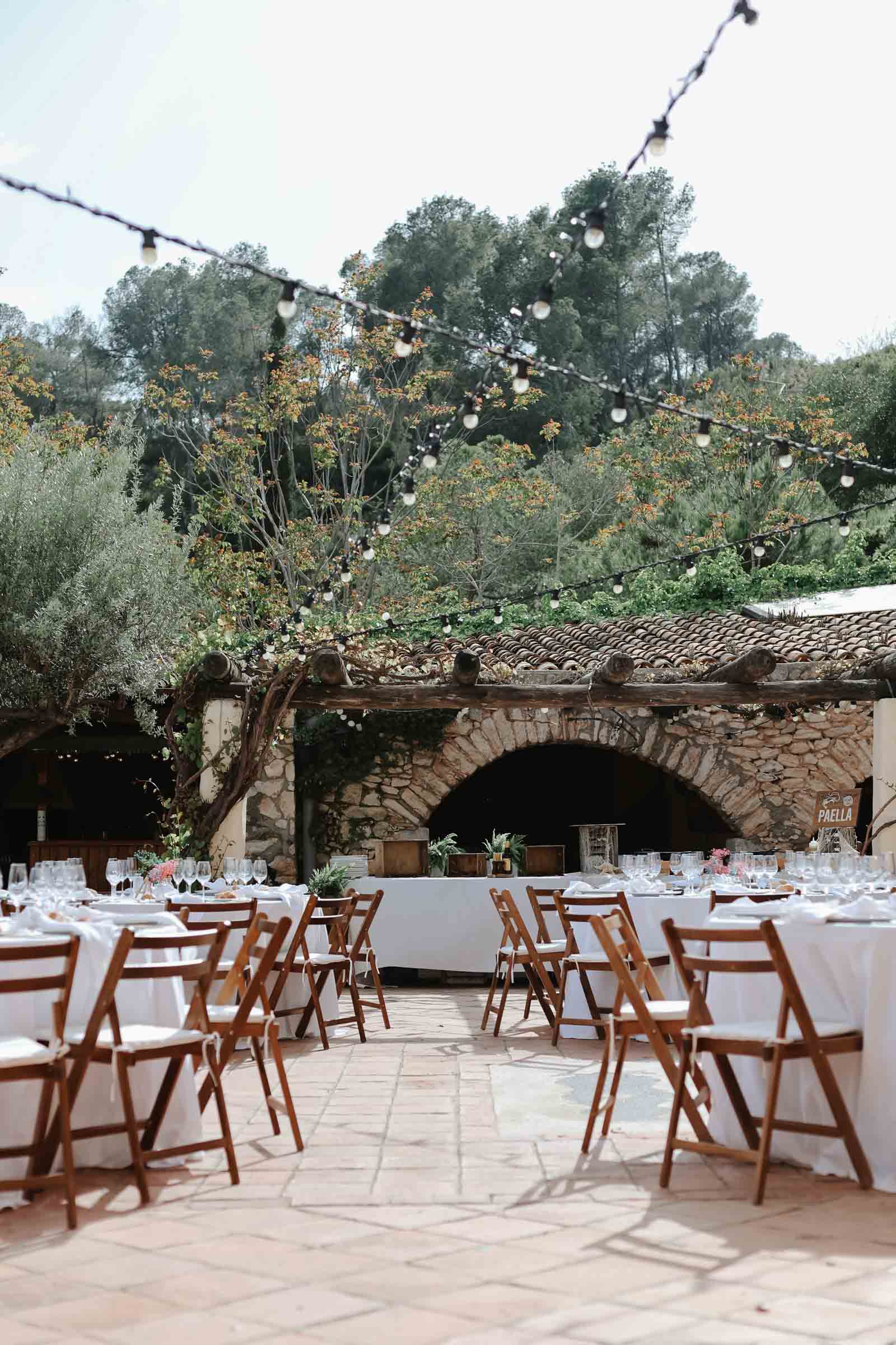 A rustic outdoor wedding venue with a clay tile roof decorated with bistro lights in Spain.