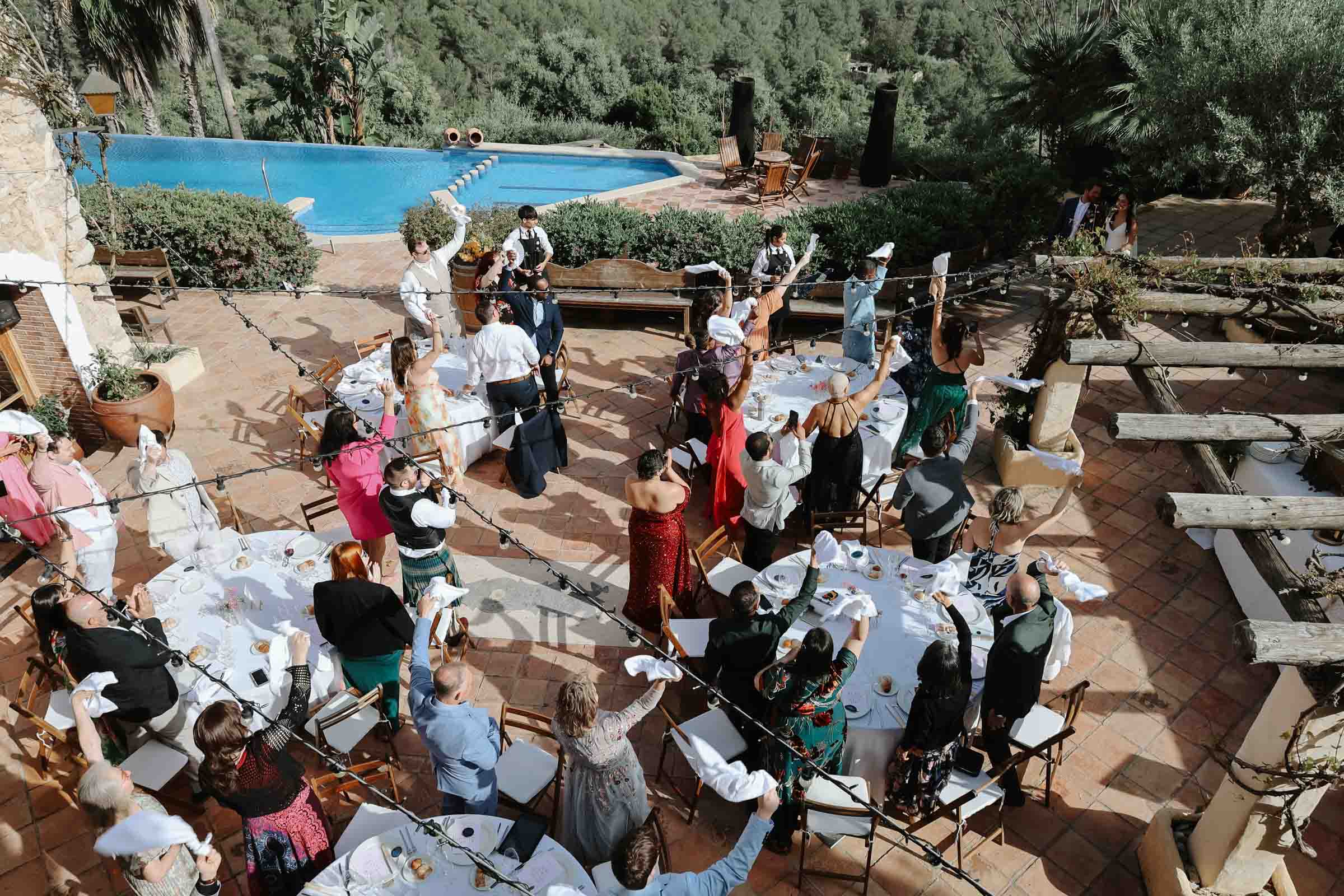 Wedding guests cheering on the bride and groom for their outdoor wedding reception on the patio of Almiral de la Font