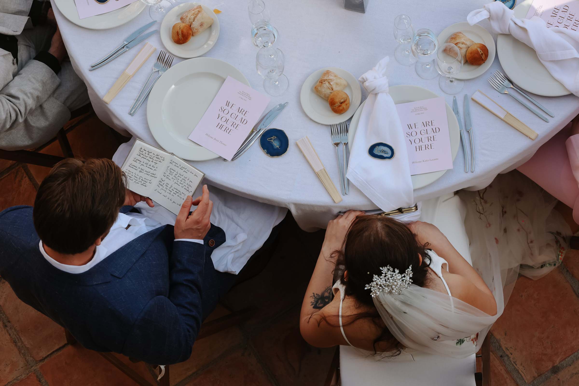 Bride and groom seated at their wedding reception table with their friends