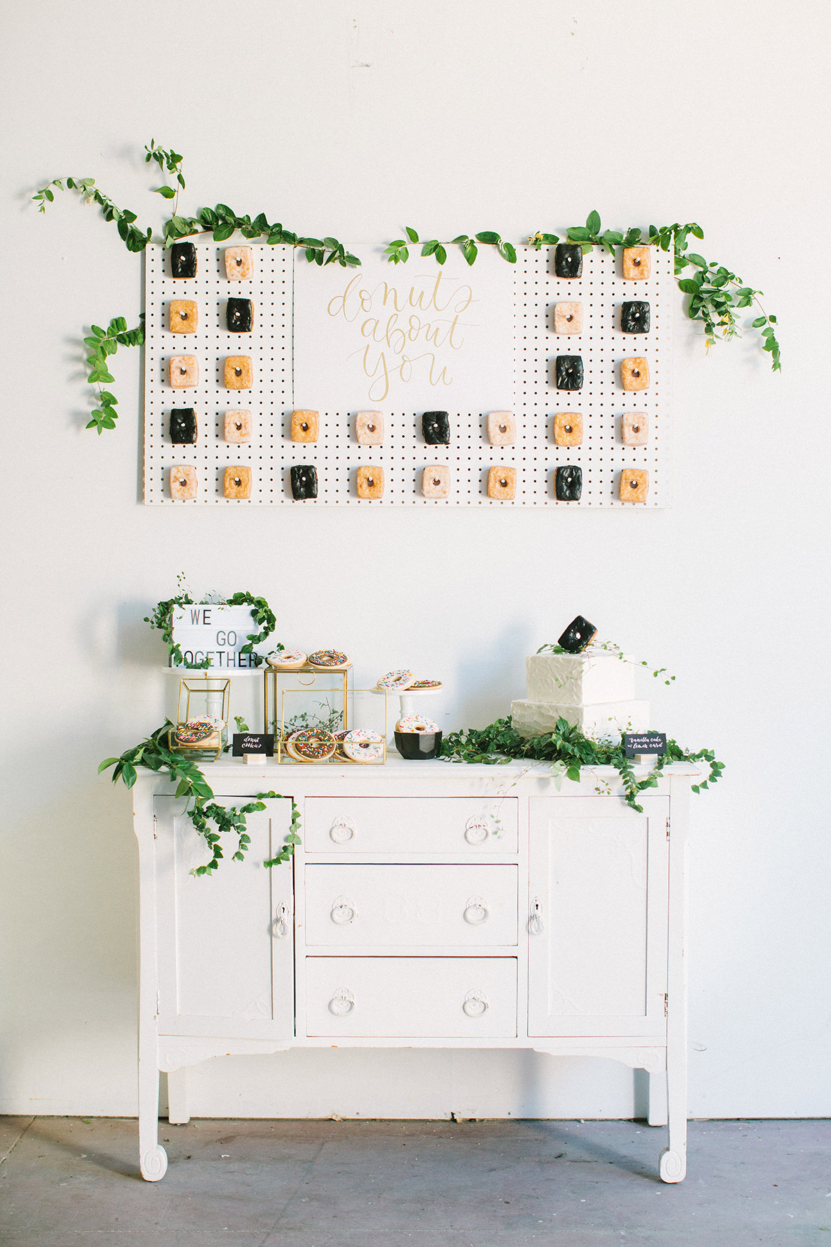 Square shaped donuts hanging on a donut pegboard wall with donut themed cookies