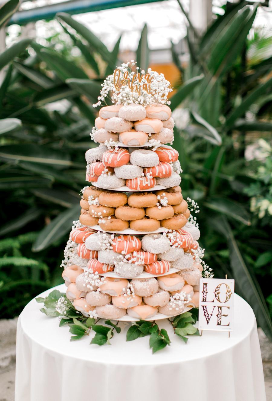 Stacked pink and peach colored donuts stacked in the form of a tiered cake