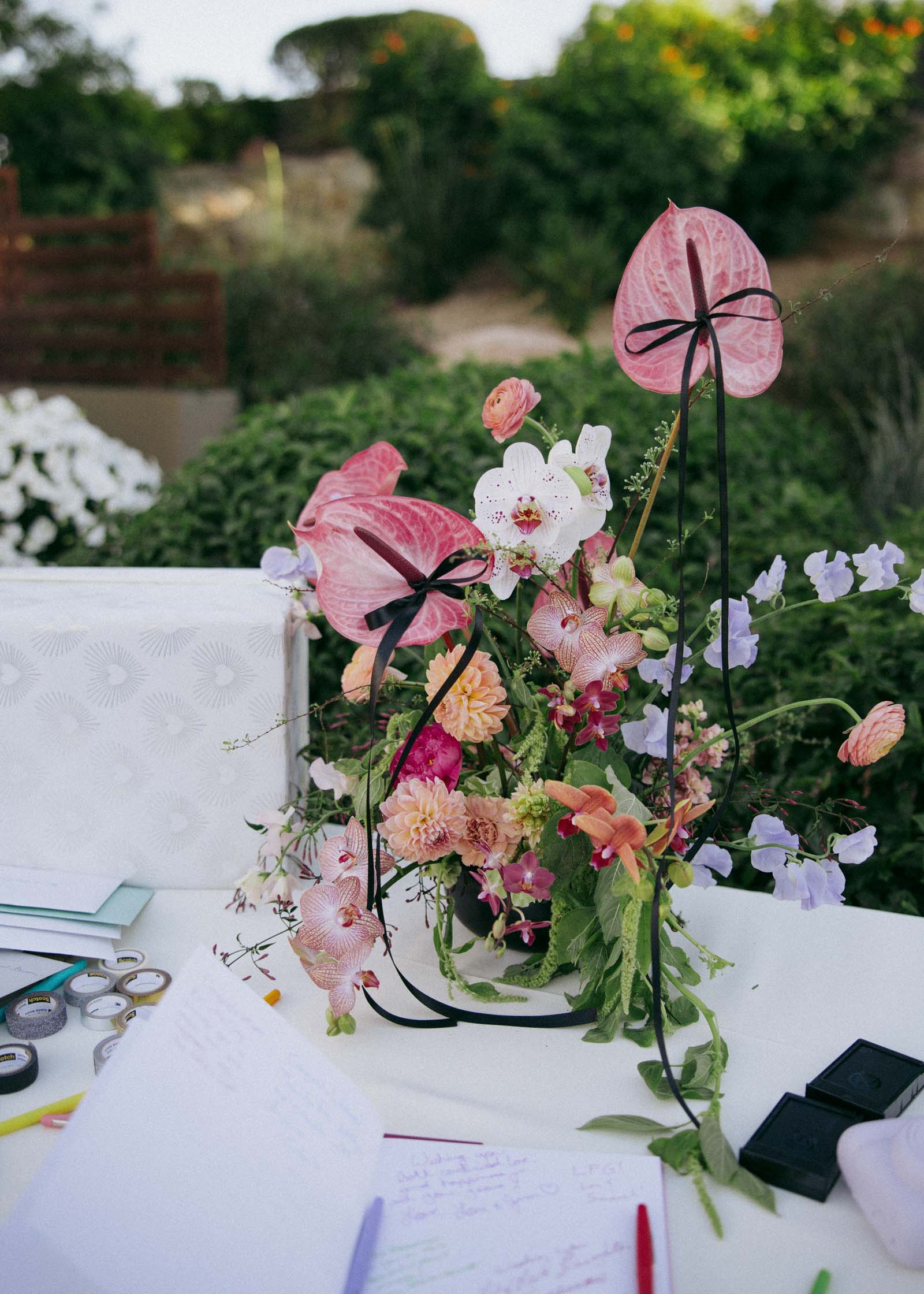 Long thin black ribbons tied onto anthurium flowers in a wedding centerpiece