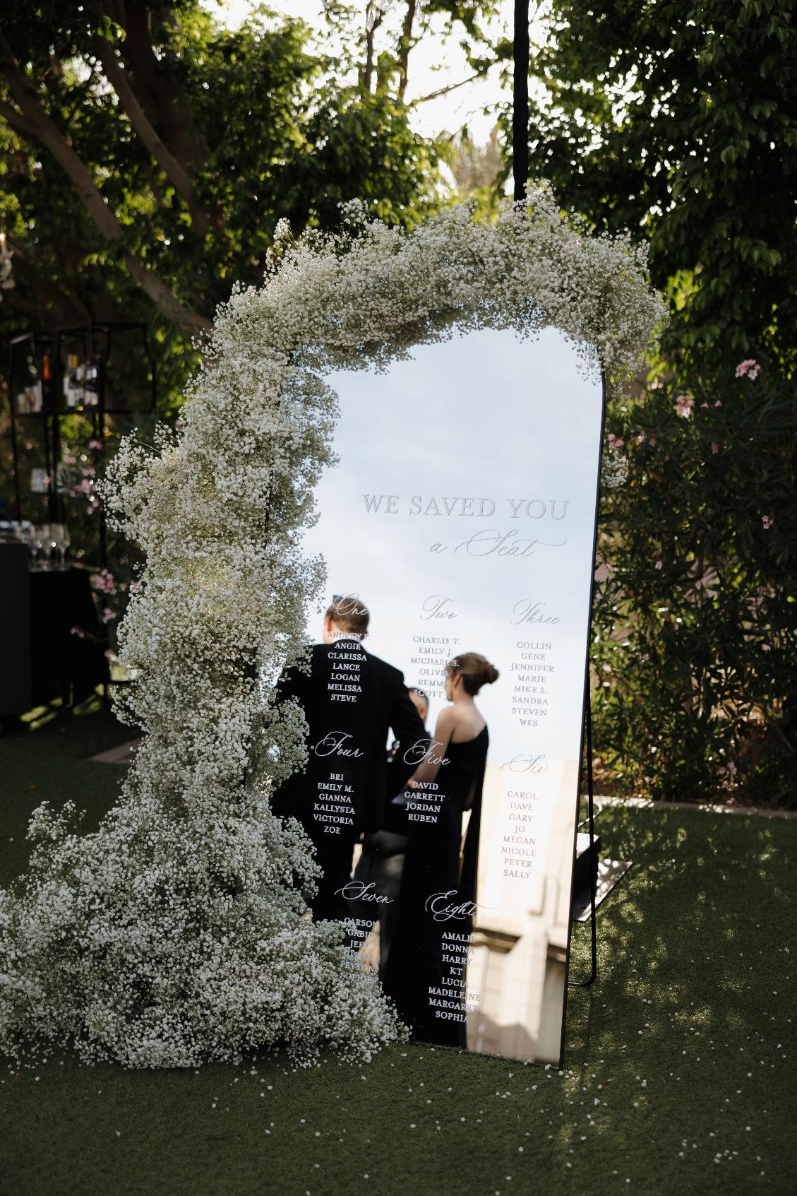 Large mirror seating chart decorated with baby's breath flowers