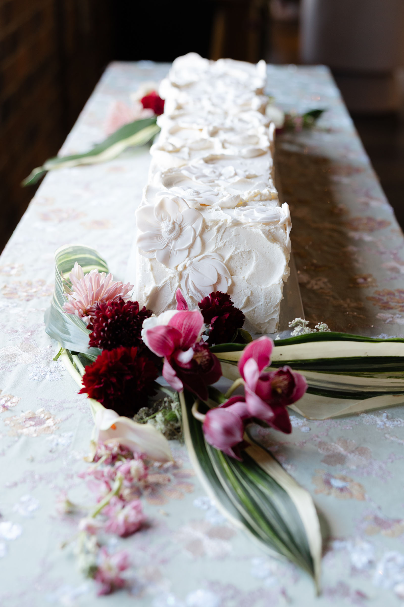 Long white wedding cake with white chocolate florals and textured icing
