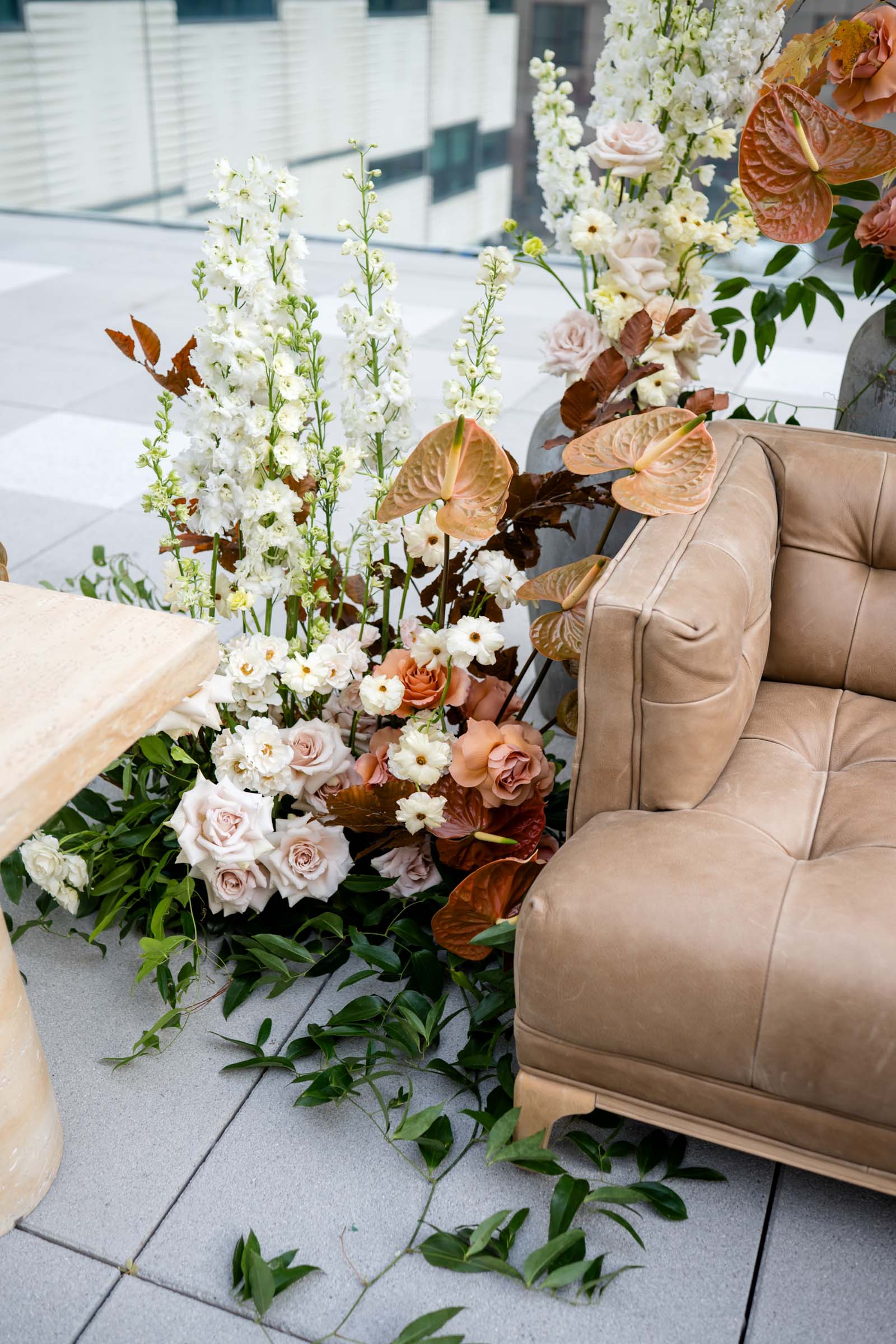 Gorgeous mushroom brown leather sofa surrounded by autumnal flowers with muted colored anthurium for fall wedding lounge ideas