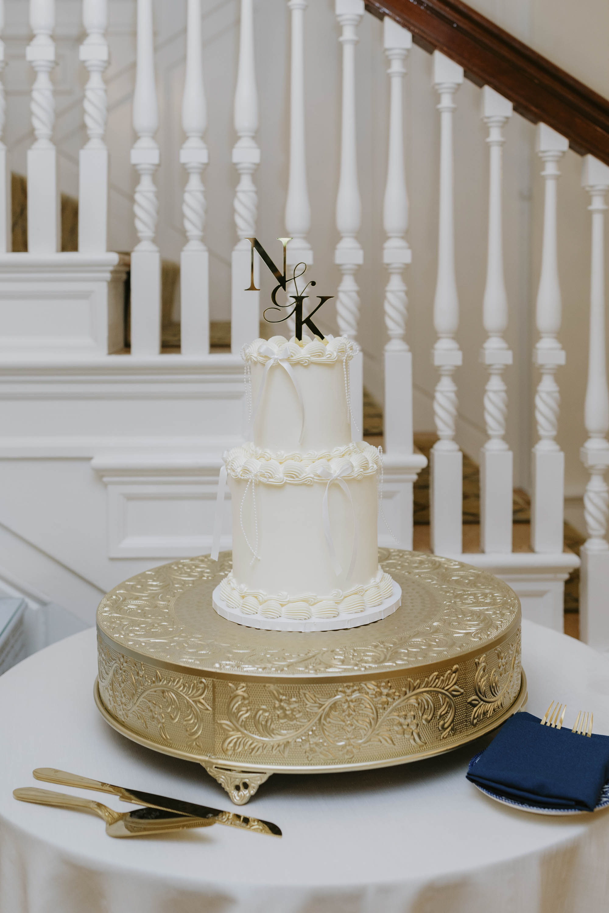 Small two tiered all white wedding cake with piping and small ribbons