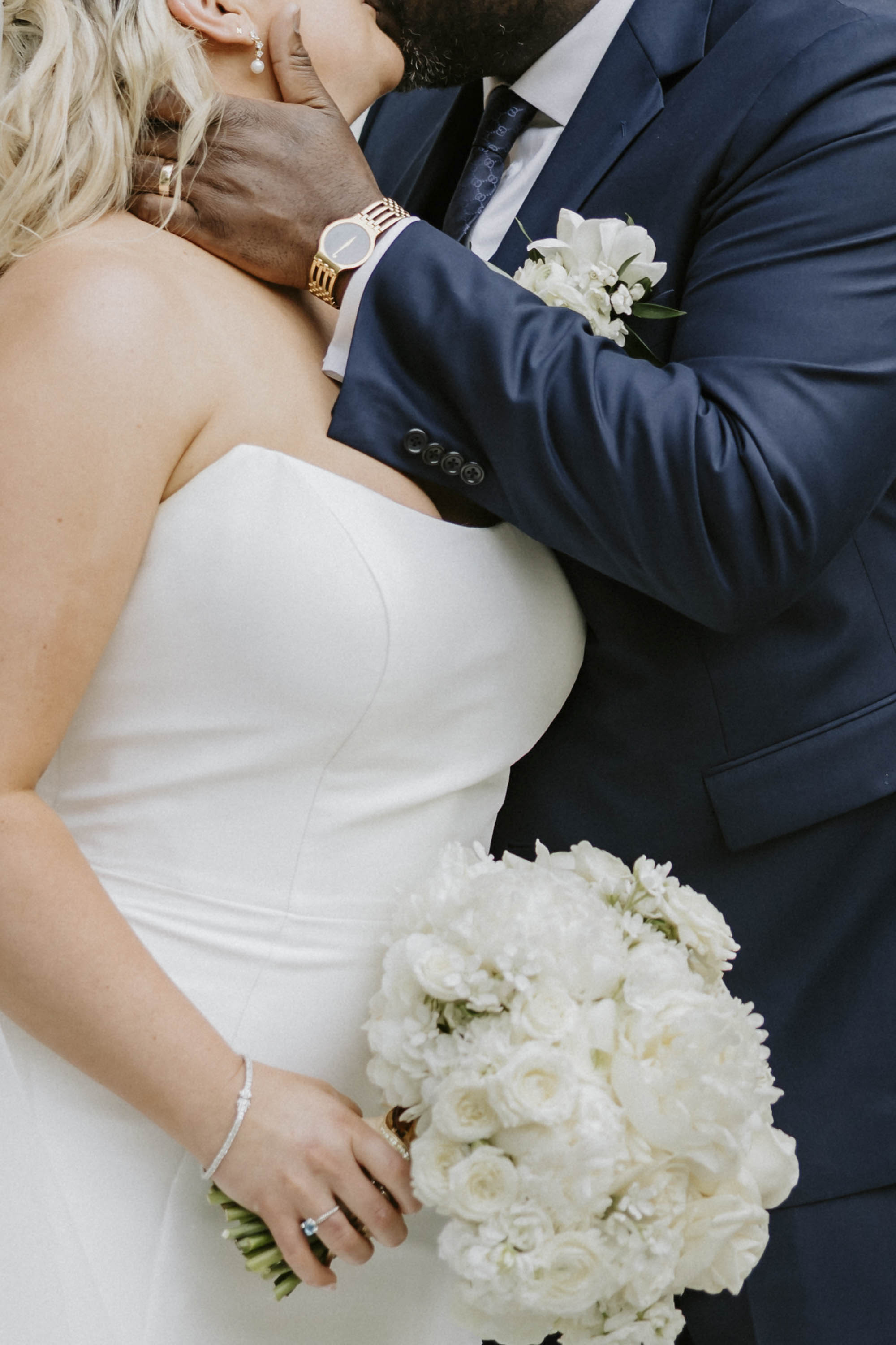 Bride wearing pointed sweetheart satin wedding gown carrying all white wedding bouquet