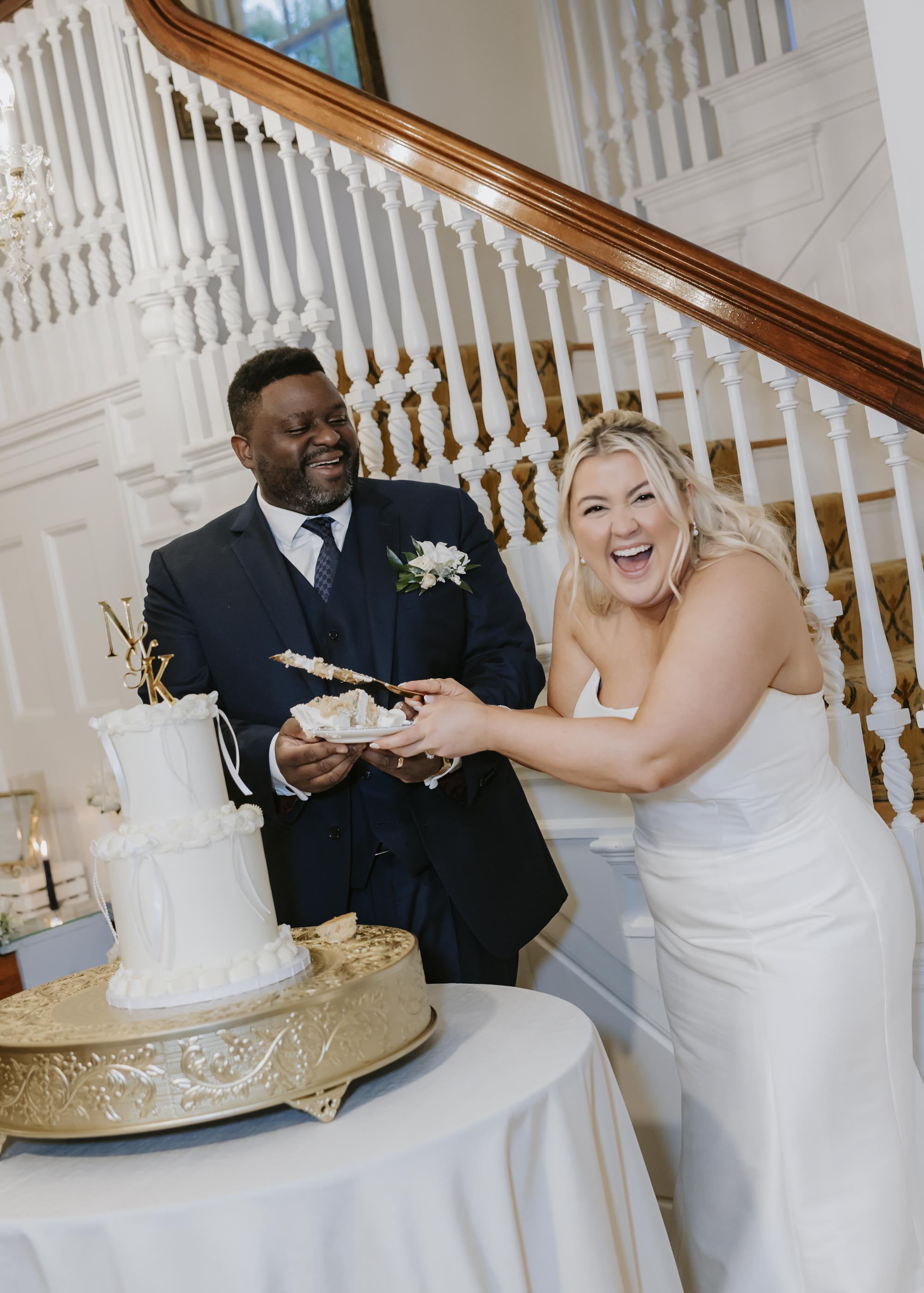 Bride and groom laughing and cutting their wedding cake