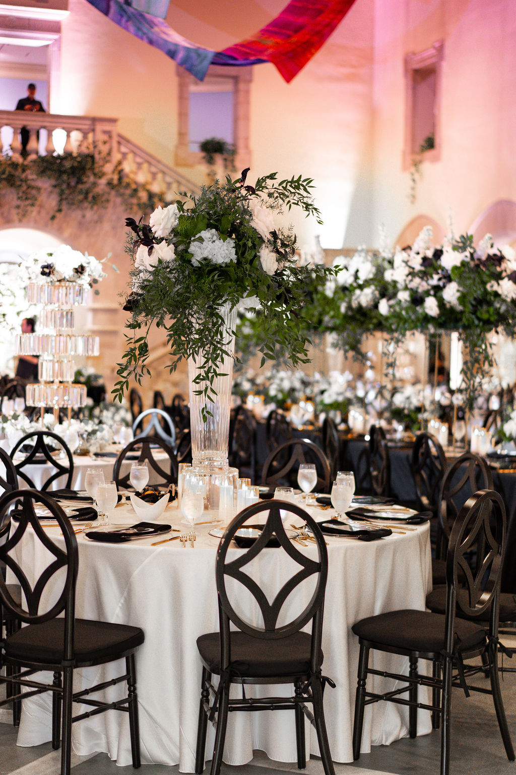 Tall white and black wedding floral centerpieces on crystal vases surrounded by LED candles