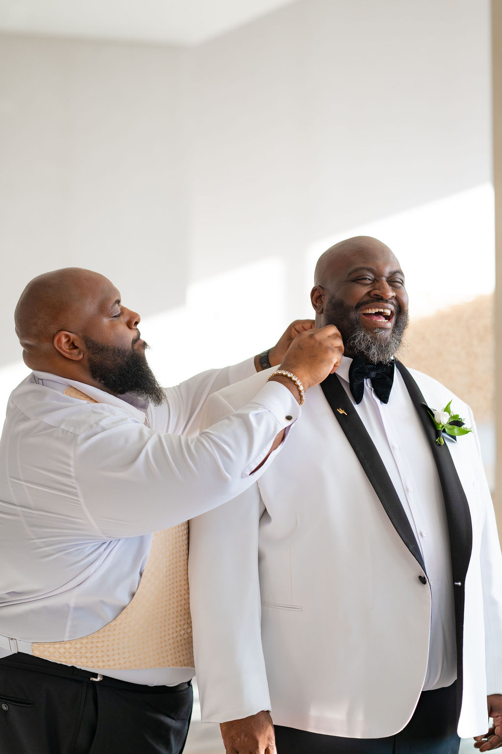 Groom getting ready with a white tuxedo and black lapels