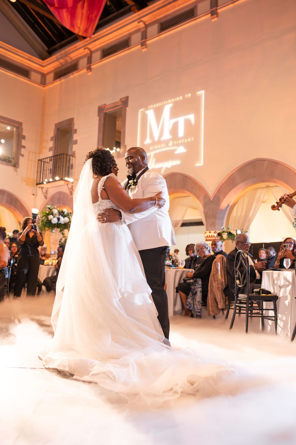 Bride and groom dance together amongst fog and custom gobo lighting logo