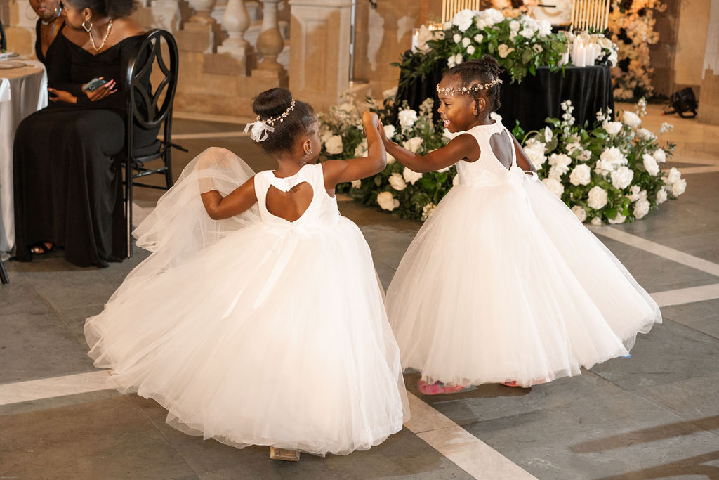 Adorable flower girls in white heart shaped dresses dancing