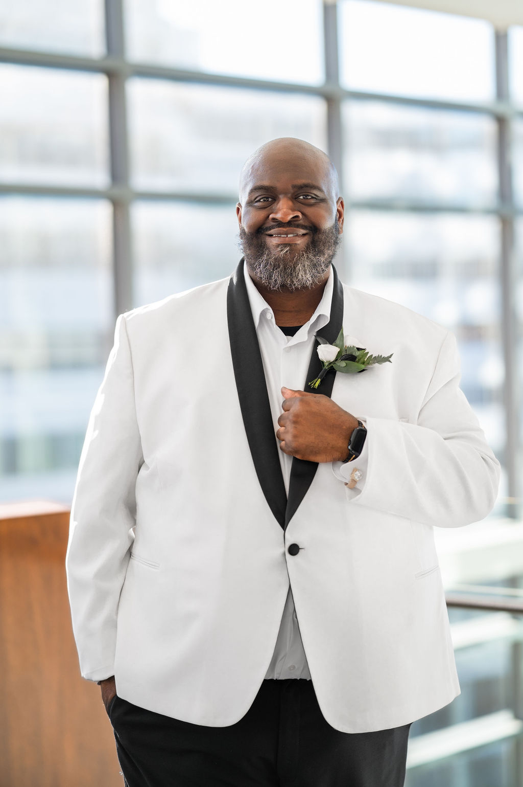 Dapper Black groom with a white tuxedo and white boutonniere on black lapel