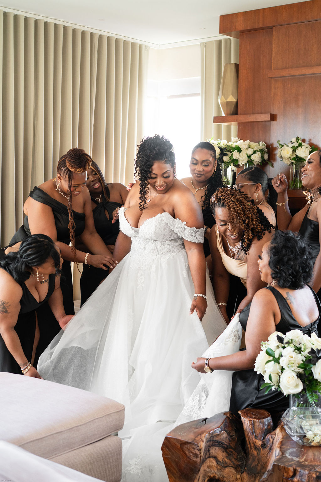 Beautiful Black bride and her bridesmaids helping get ready on the wedding day