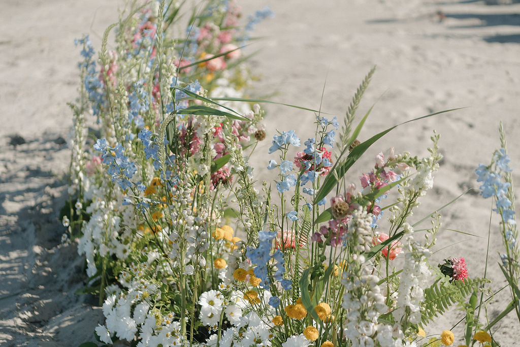 Meadow and beach inspired grounded wedding ceremony florals for a seaside celebration