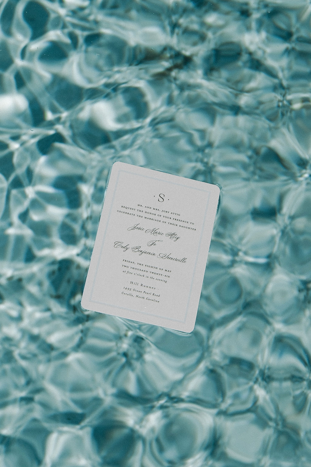 Elegant modern beach wedding invitation floating in a pool for unique shot