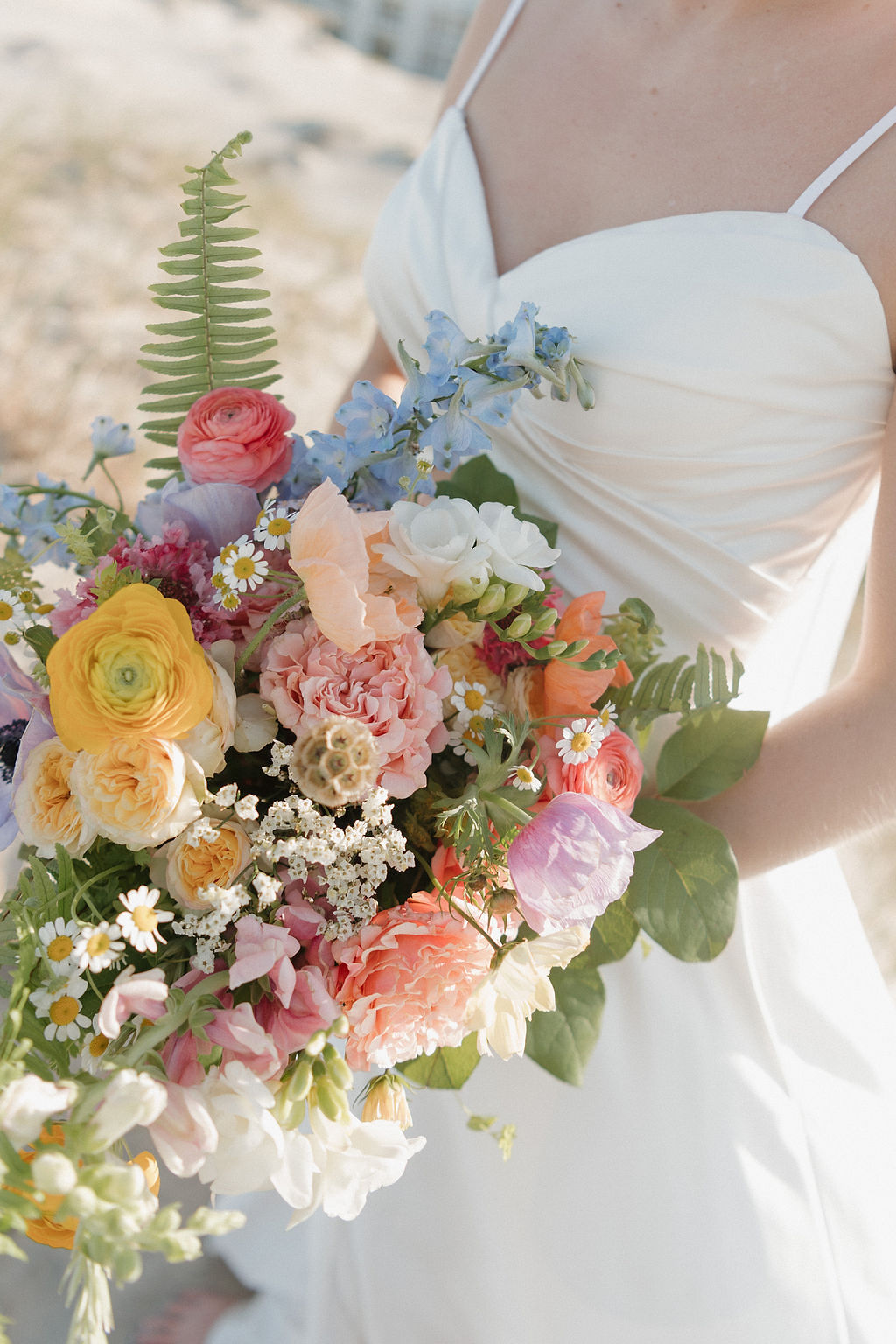 Colorful pastel wedding bouquet with ranunculus, daisies, and roses