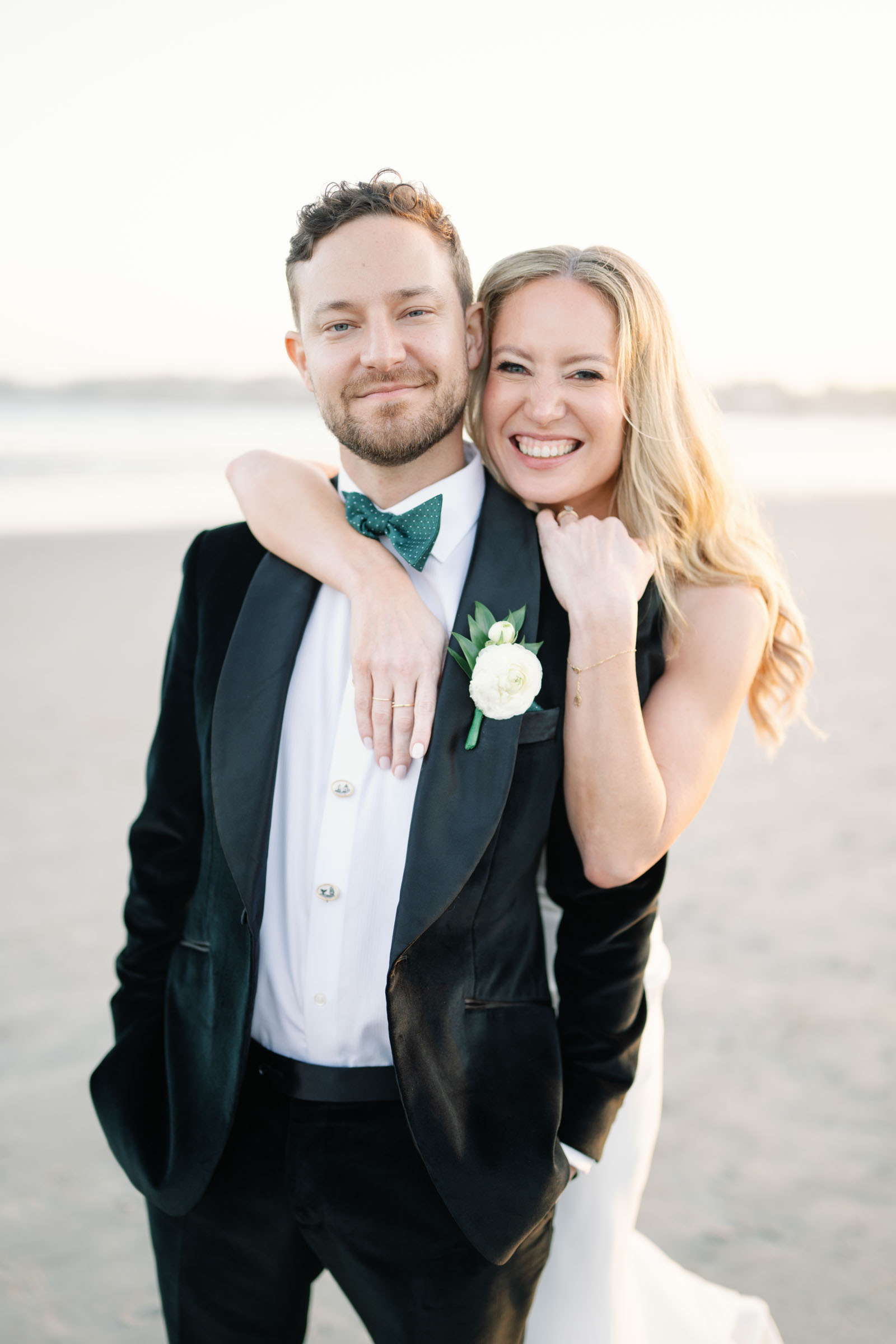 Groom wearing emerald green bow tie with vintage nautical buttons in a black velvet tuxedo
