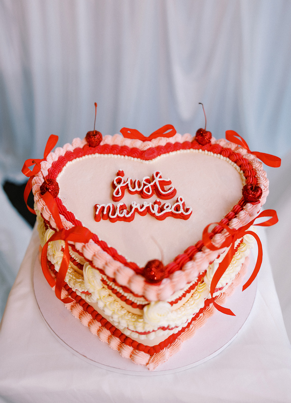 Red and pink lambeth vintage style wedding cake with red bows and cherries