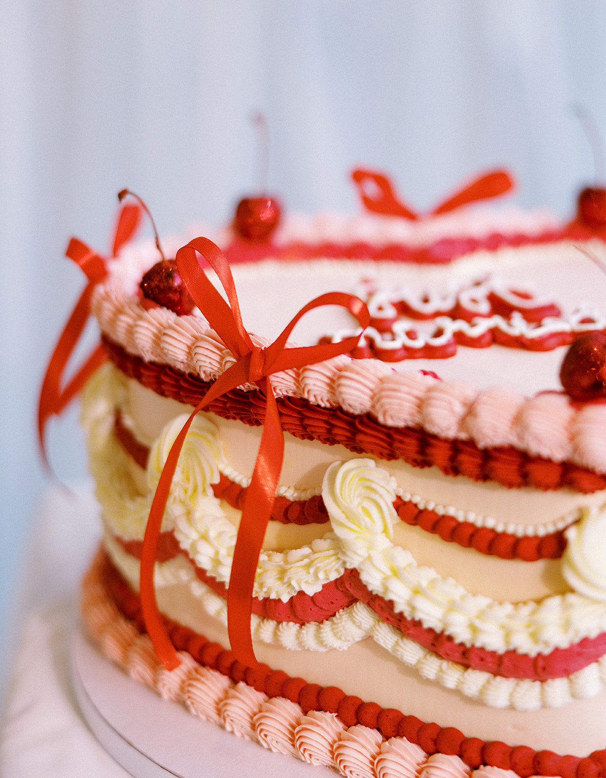 Red and pink lambeth vintage style wedding cake with red bows and cherries