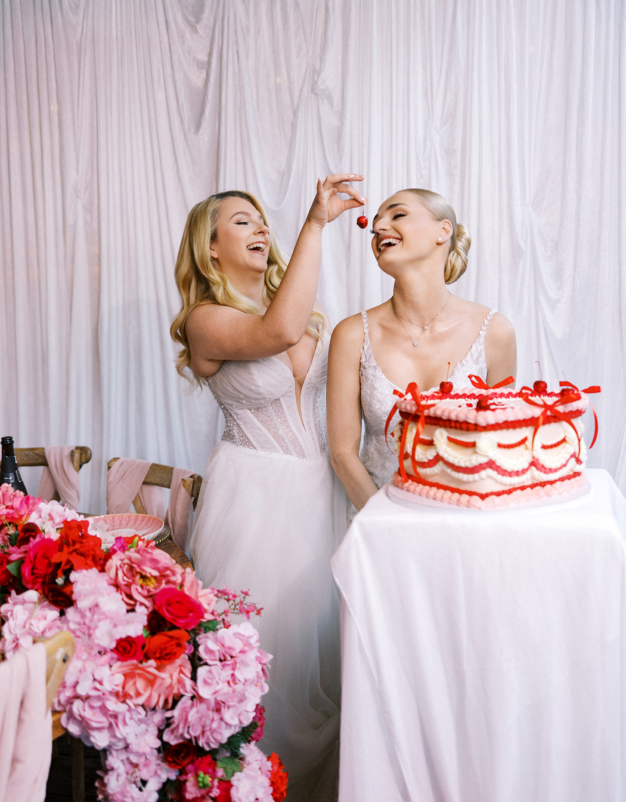 Two brides enjoying a lambeth style wedding cake with glitter cherries