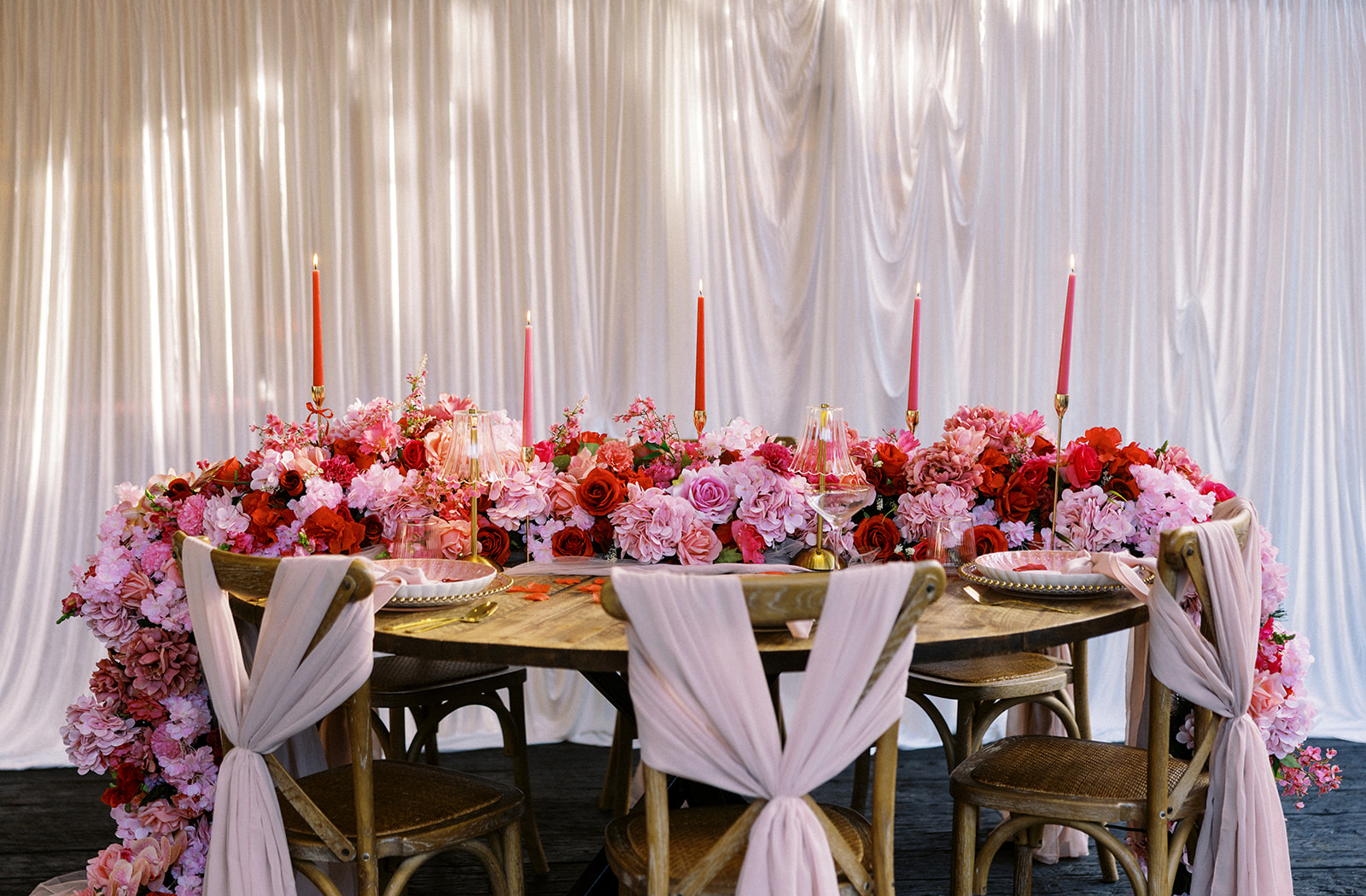 Red and pink wedding reception table decor ideas with candles and floral centerpiece garland