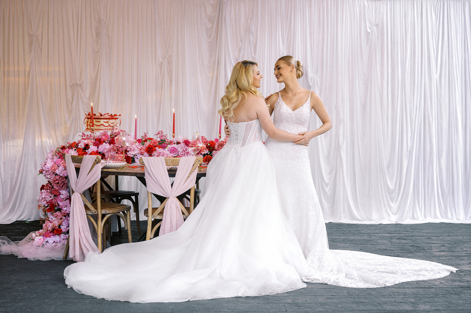 Two brides having a sweet moment during the pink and red wedding reception at The Glasshouse in Kent England