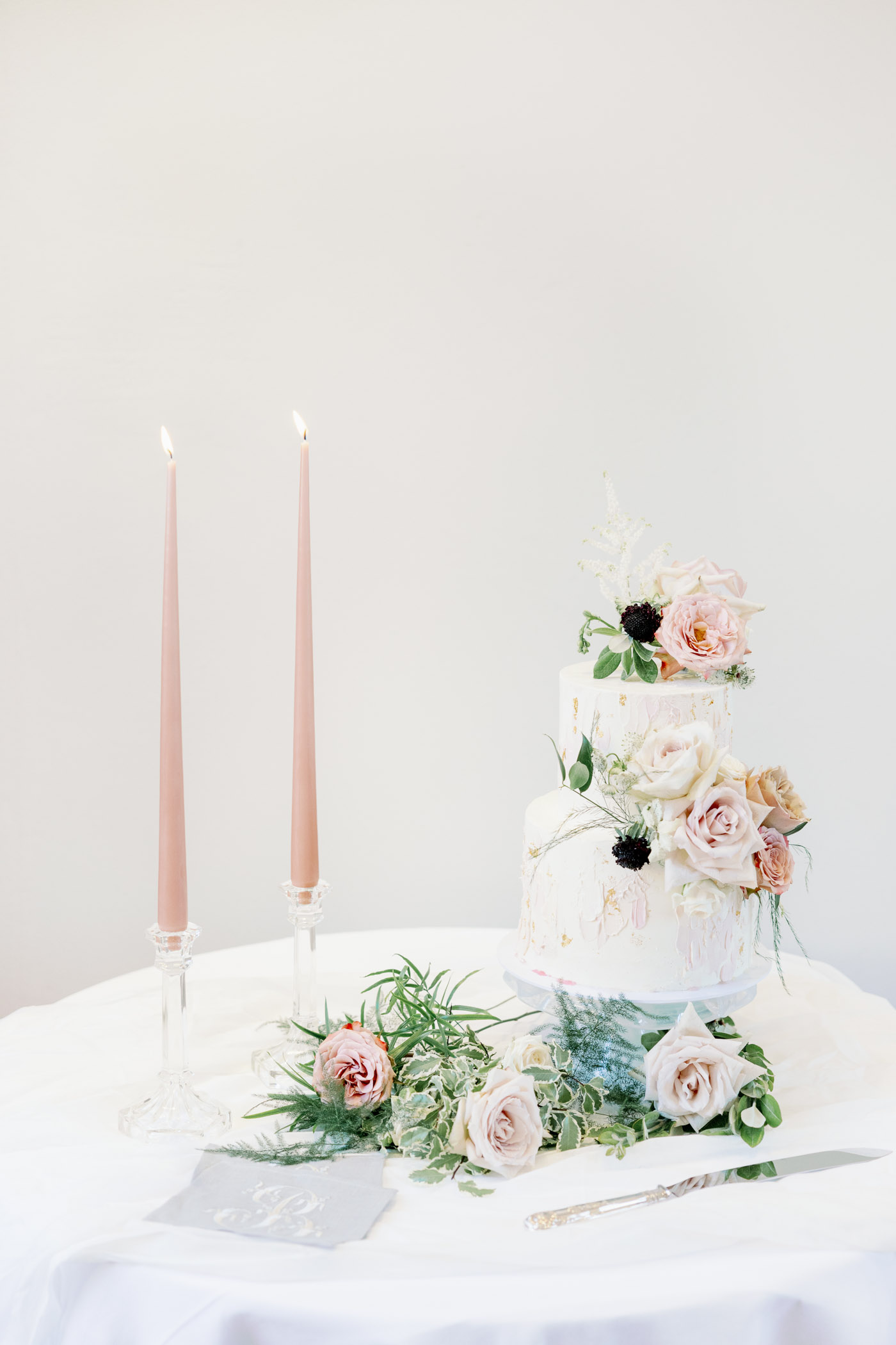 Pastel painterly wedding cake styled with pink candles and flowers