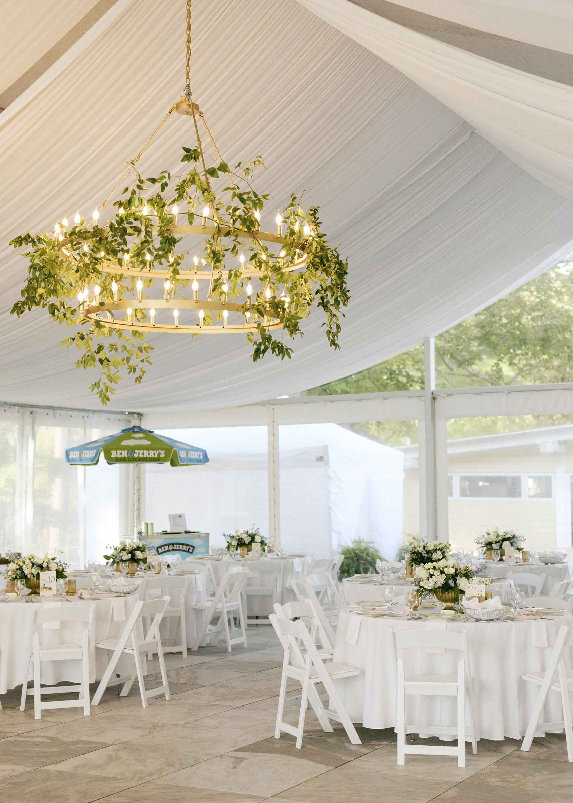 Tented wedding reception with ceiling draping and a greenery chandelier that has a Ben and Jerrys ice cream cart in the background