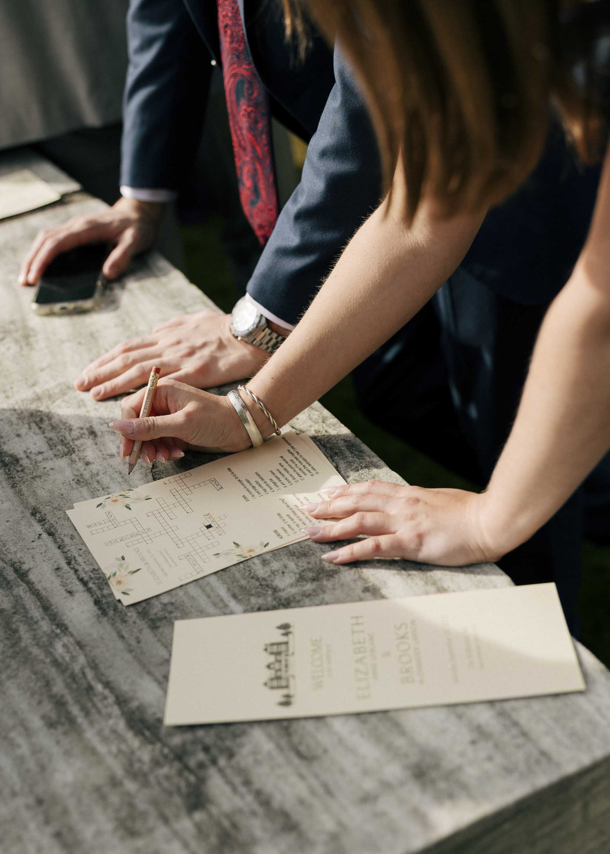Guests doing wedding crossword puzzle about the bride and groom