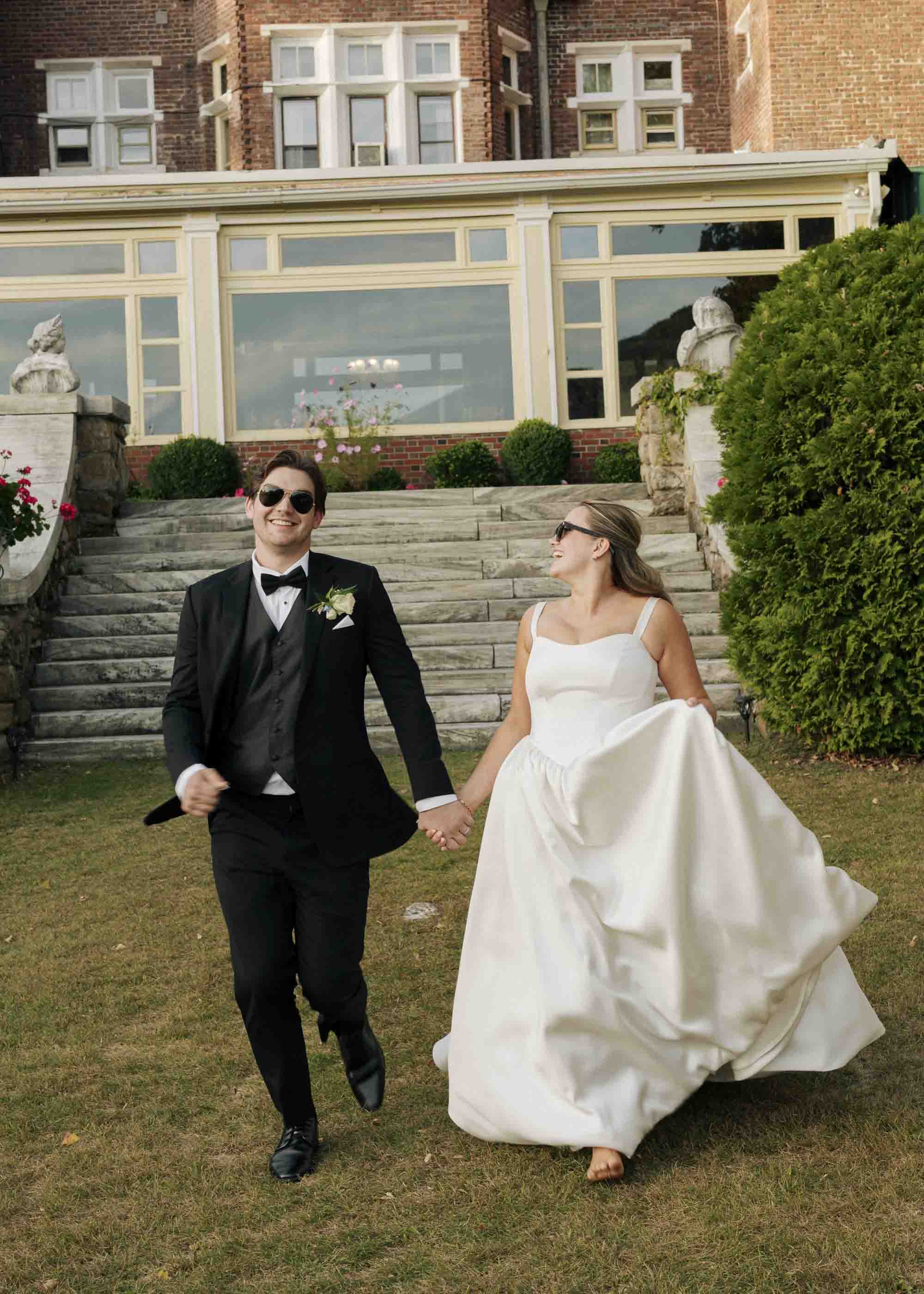 Bride and groom wearing sunglasses and running happily at the Wilburton in Vermont