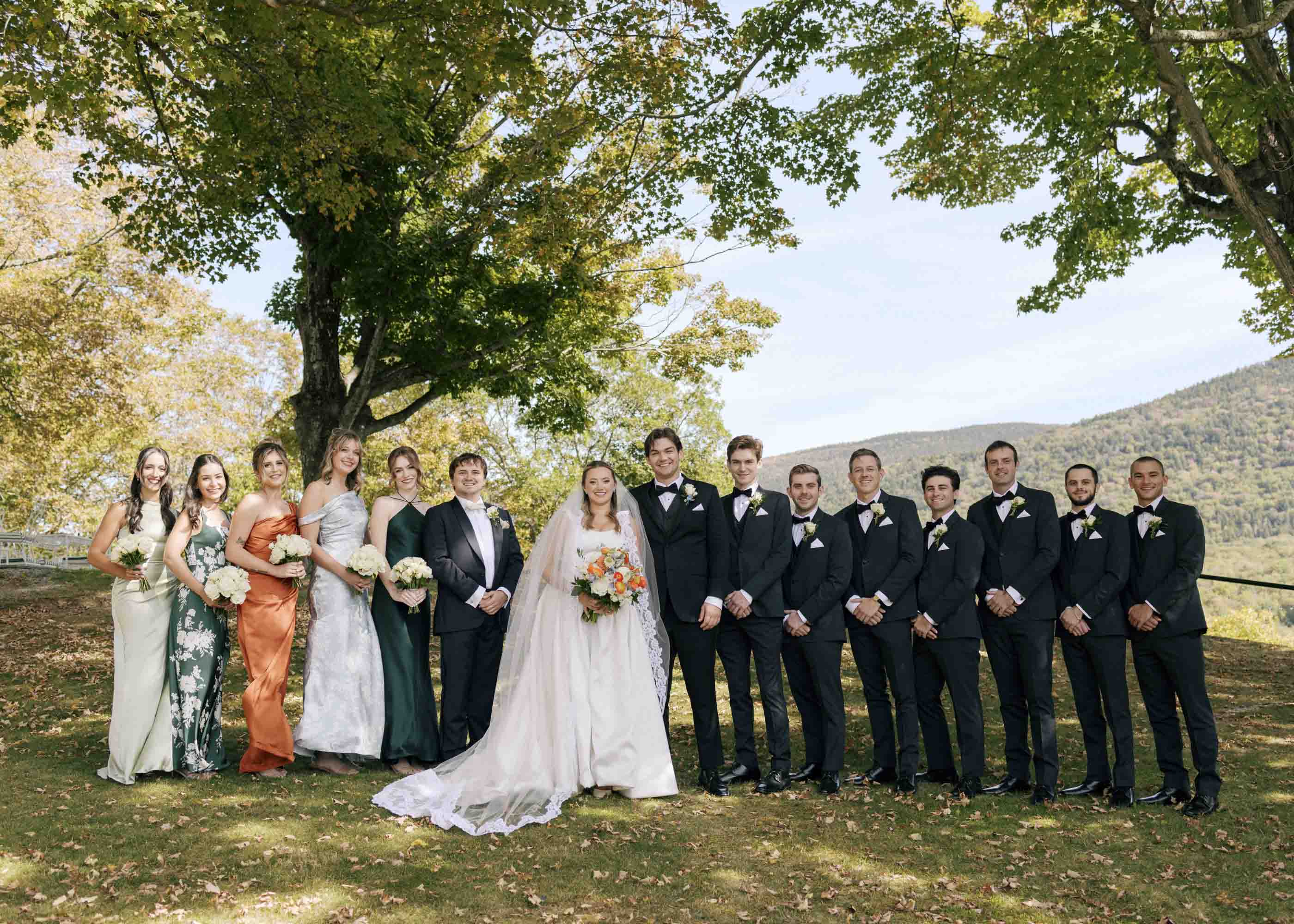 Wedding party in orange and green dresses and black suits
