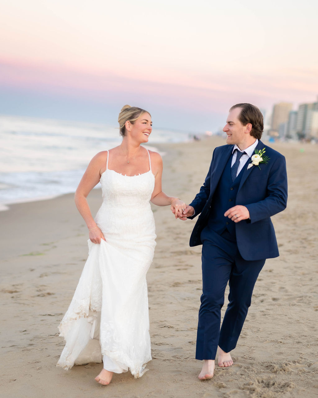 A newly married bride and groom running on the beach at Virginia Beach Oceanfront during sunset