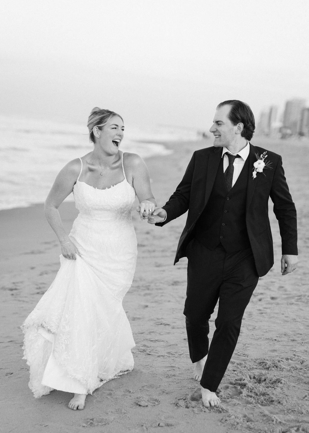 A newly married bride and groom running on the beach at Virginia Beach Oceanfront during sunset
