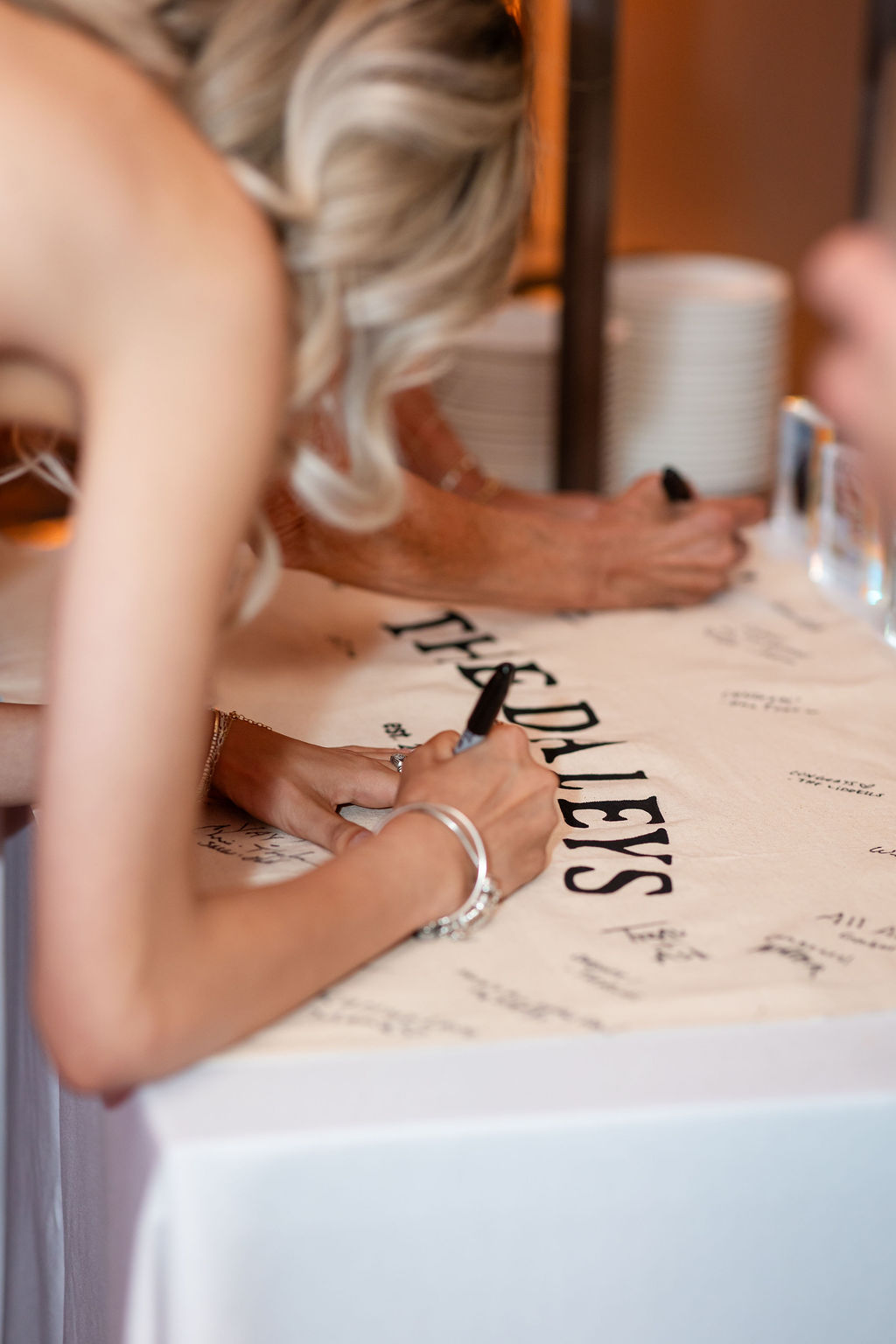 Guests signing unique wedding guest book banner with the couples new last name