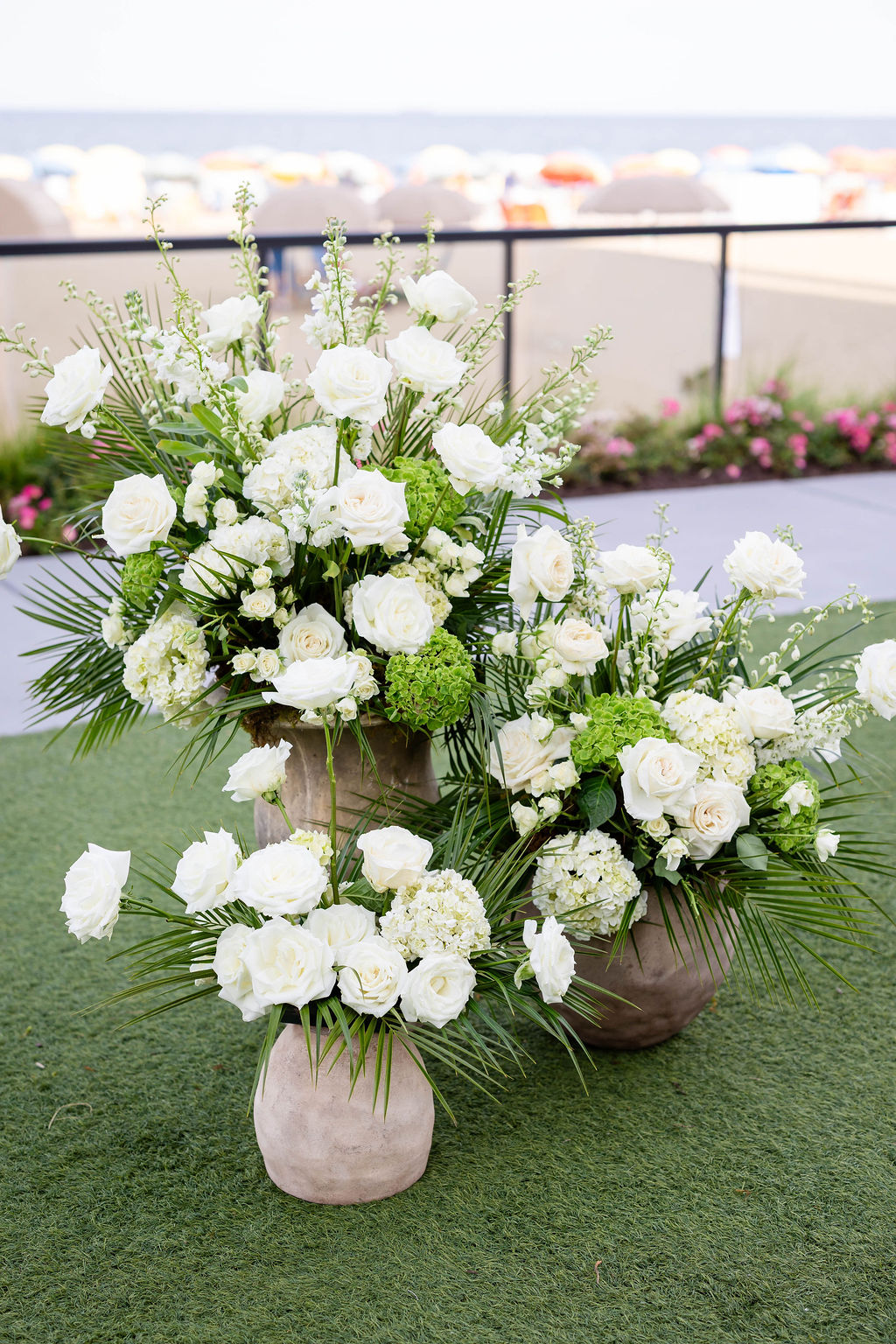 All white wedding ceremony florals with roses and palm leaves