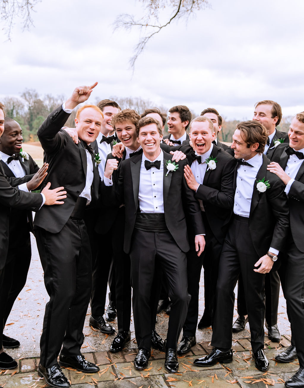 Groom and his groomsmen wearing classic black tuxedos and suits for country club wedding
