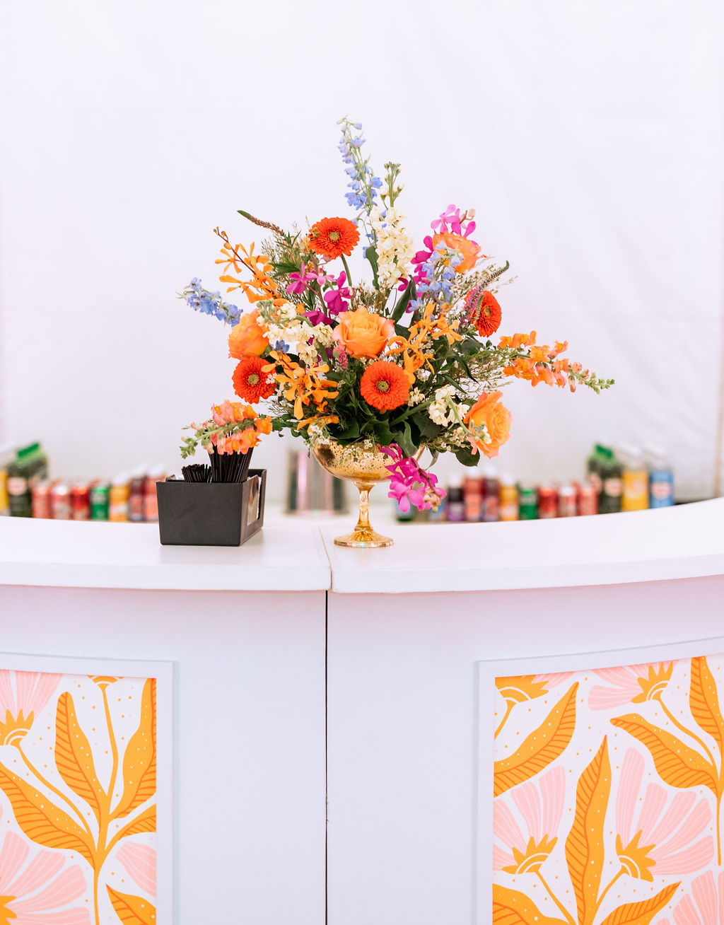 Bold and colorful bright orange and pink wedding flower arrangement for the bar
