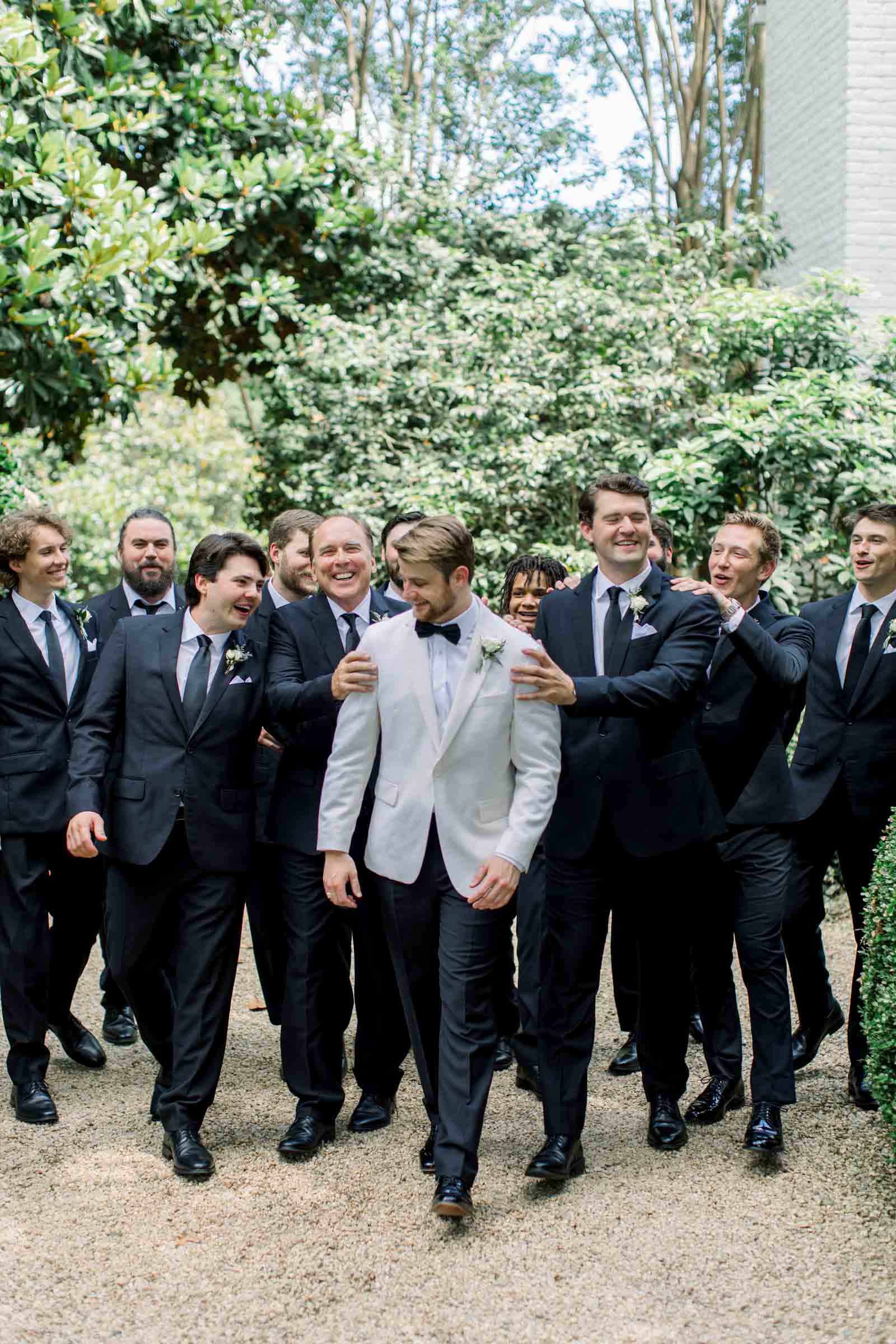 Groom and his groomsmean in white and black tuxedos for vintage inspired wedding