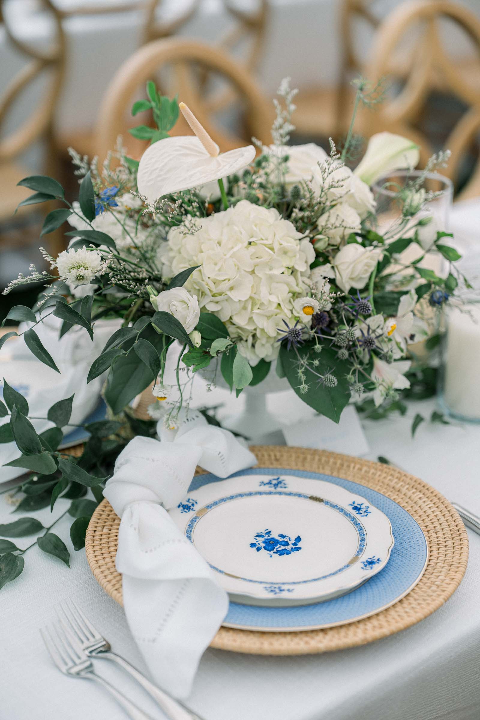 Small wedding centerpiece with white anthurium and hydrangeas alongside white and black vintage plates